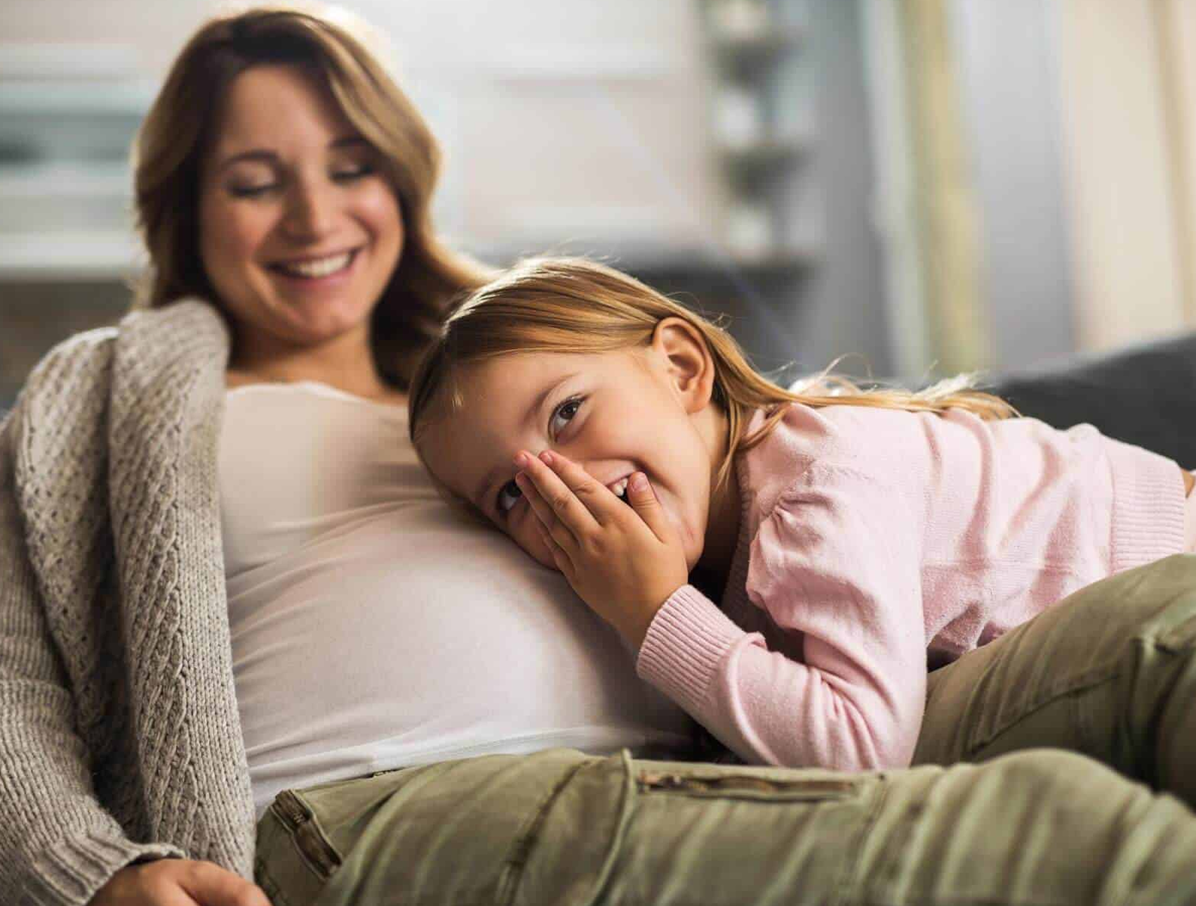 Schwangere Mutter mit Kind auf einem Sofa